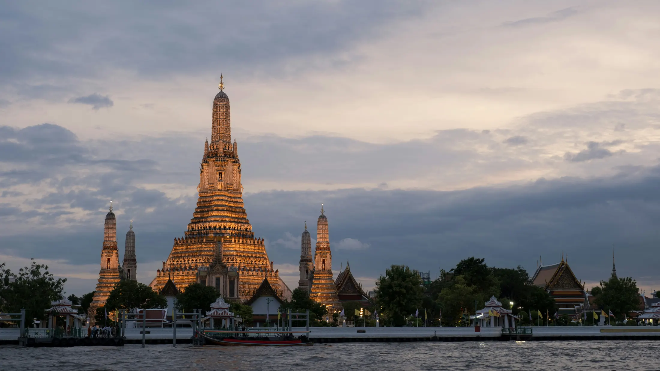 Wat Arun temple lit at dusk above the Chao Phraya river in Bangkok