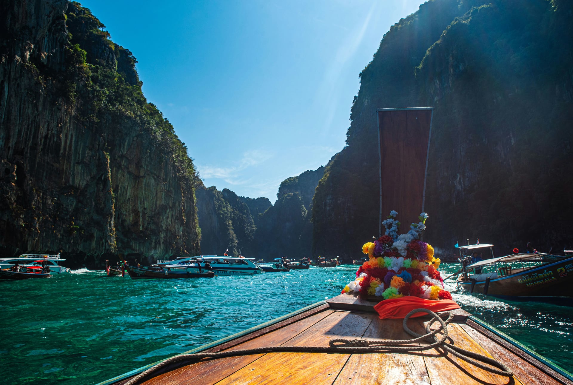 Kayak gliding across turquoise water between towering limestone cliffs in southern Thailand.