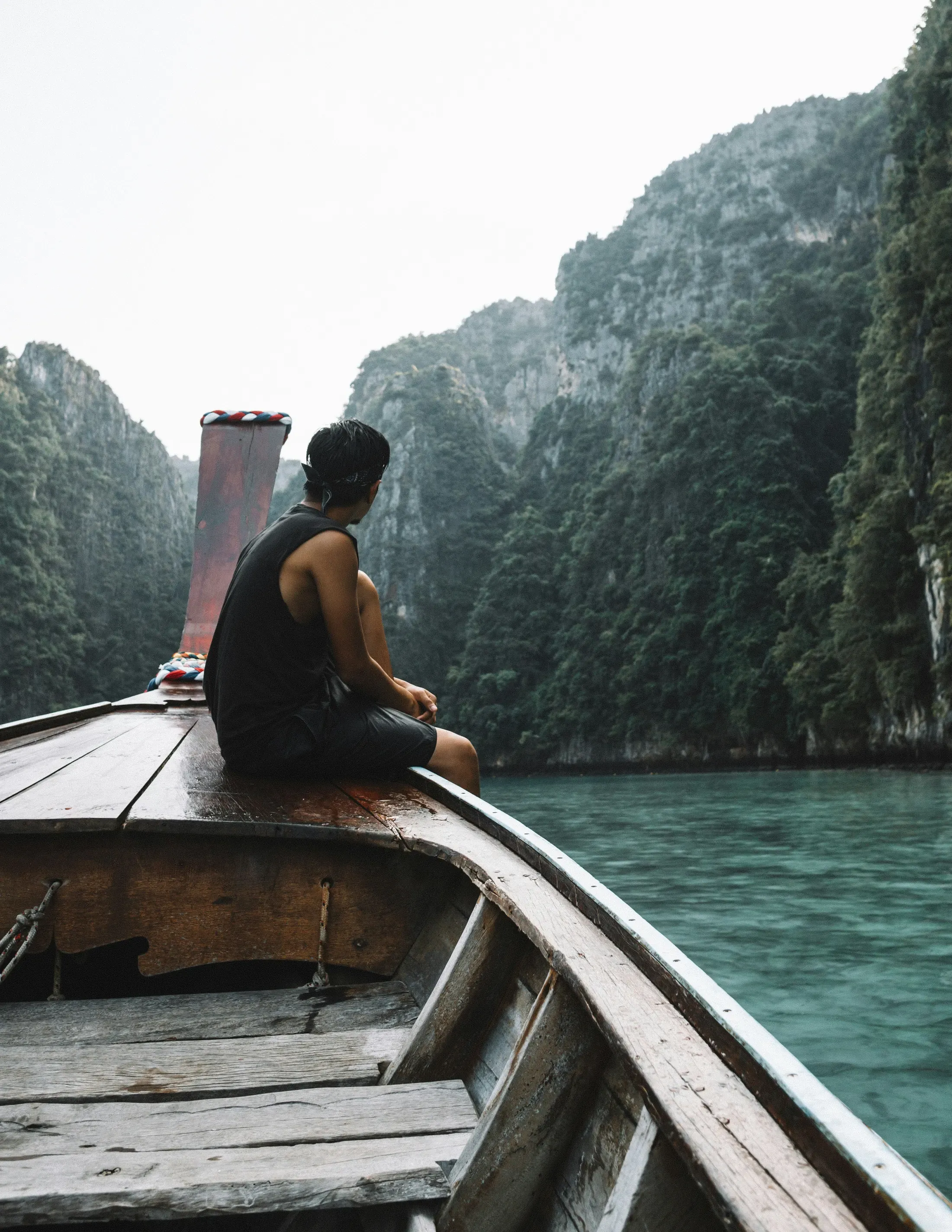 Traveller on the bow of a private longtail boat among limestone cliffs in southern Thailand